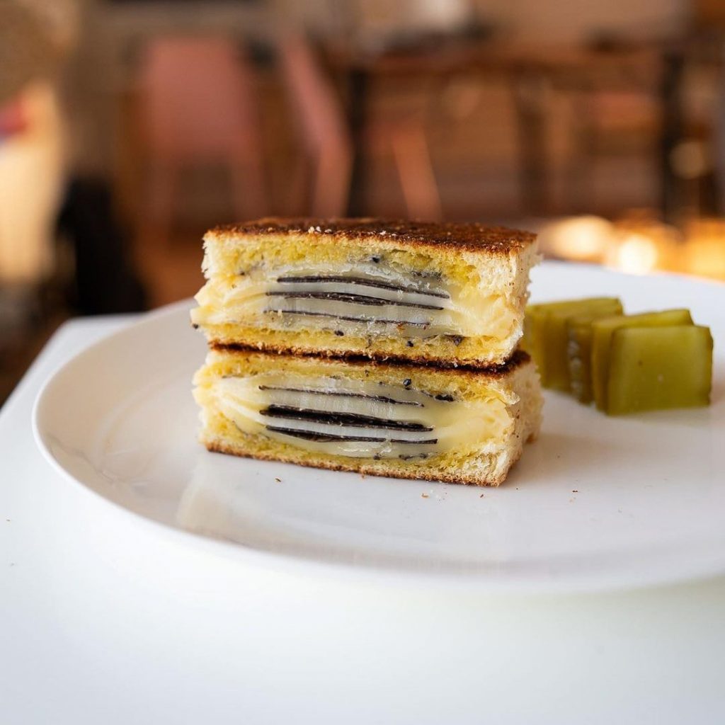 Black truffle grilled cheese sandwich cut in half, showing layers of cheese and truffle