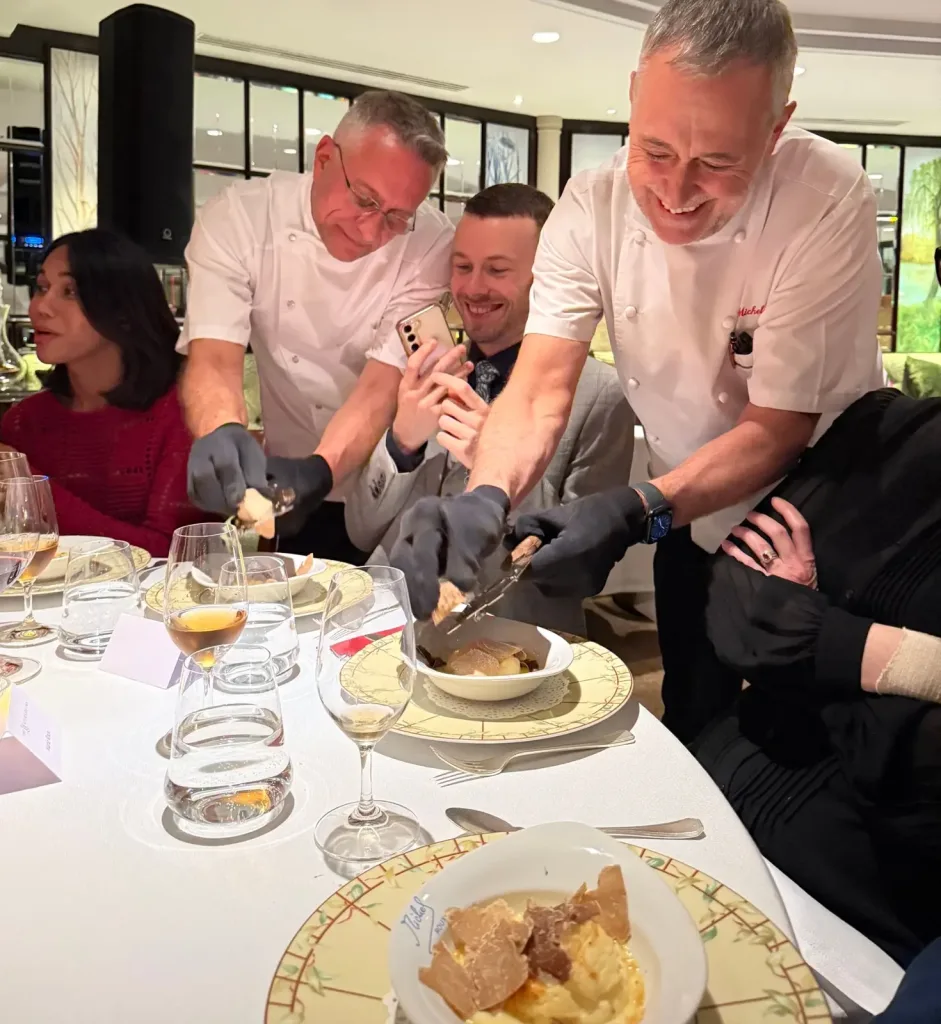 Alain Roux and Michel Roux Jr. shaving white truffle over Soufflé Suissesse at the table